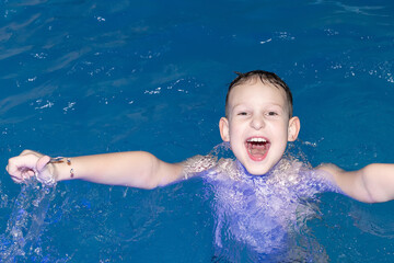 Fototapeta na wymiar A Beautiful happy boy swims in the pool