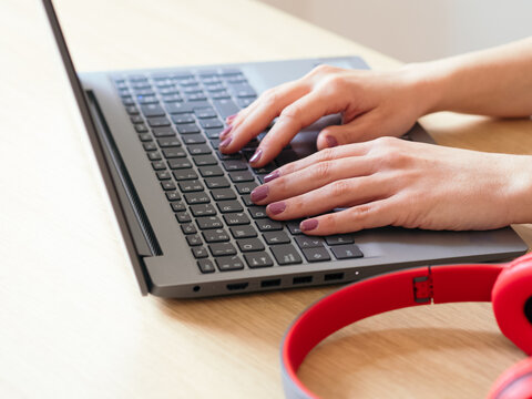 Detail Of A Woman's Hands With Purple Painted Nails Typing A Laptop