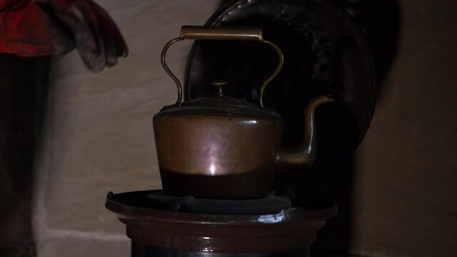 Making drink on vintage copper kettle on a log burner in hearth