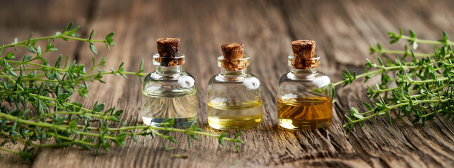Panoramic header of essential oil bottles with fresh thyme twigs - obrazy, fototapety, plakaty