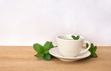 Leaves mint ( Mentha ) and cup mint tea on a light background