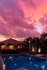 A gentle sunset sky over a thatched bungalow. An exotic resort in the tropics