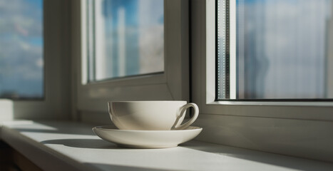 Cup and saucer on the windowsill made of plastic