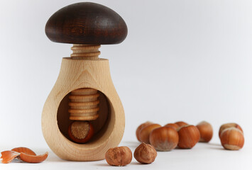 Homemade wooden tool for cracking nuts close-up on a background of hazelnut.