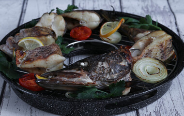 Freshly griled pike with lemon,tomato and onion on a black background.