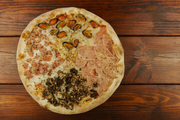 Pizza with shrimp, mussels, ham and mushrooms. On a wooden table