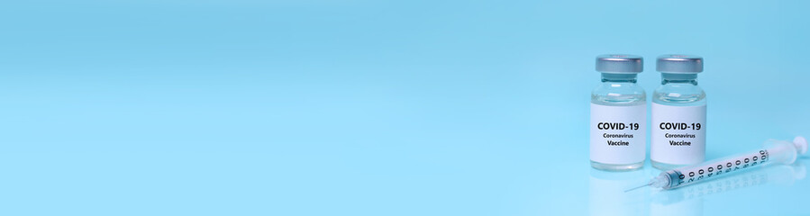 Vaccine in a bottle with a syringe on a blue background. Syringe, two vials (two doses) of coronavirus vaccine.The concept of medicine, healthcare and science..Copy space for text.Banner