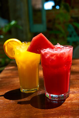 Two glass glasses with refreshing drinks from orange and watermelon juice.