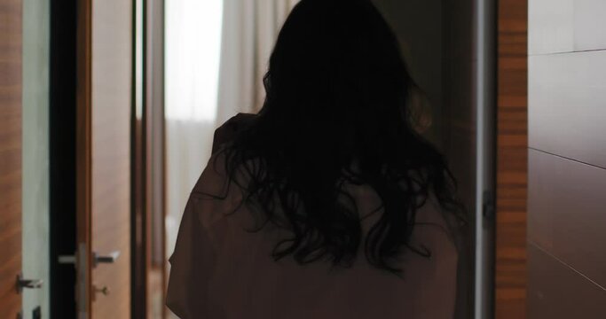 Young woman with long hairs going through cozy luxury hotel room, 4k back view video