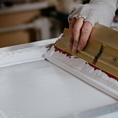 selective focus photo of male hand with squeegee. serigraphy production. printing images on...