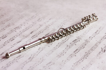 music woodwind instrument - Brass silver metal flute on a beautiful sheet music background