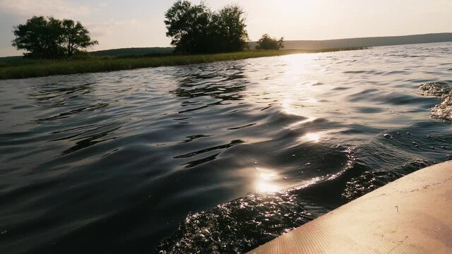 Boat traveling. Water journey. Enjoying nature. Leisure relax. Rubber ship going on river surface with sunlight flacks green trees shore on horizon .