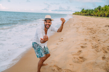 Friendly young Latin American man inviting to come to Brazil, confident and smiling making a gesture with his hand, being positive and friendly