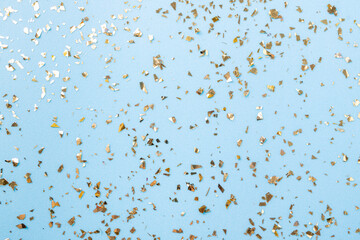 Golden flying sparkles on blue fashion holiday background. Festive backdrop. Texture of golden glitter on blue