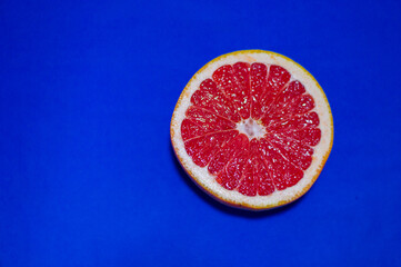 Piece of red grapefruit on isolated blue background.
