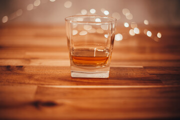 Glass voll whisky auf einem Holztisch mit Lichtern im Hintergrund. Bokeh