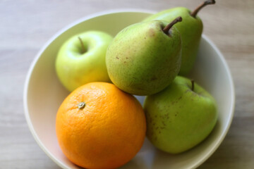 Bowl with pears, appples and oranges on a table. Selective focus.