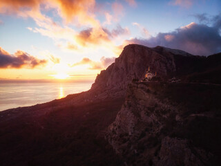 Fototapeta premium Epic high mountain church scenery aerial view. Drone epic landscape view. Colorful clouds