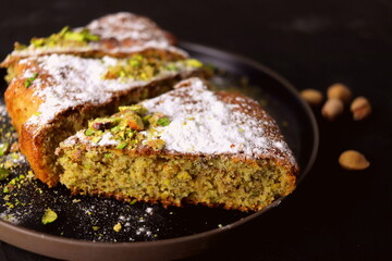 appetizing baked pie cut into slices pistachio on a black background close-up.