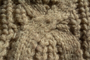 Close-up of the central twist of a large knitted jumper. English knit. Beige, natural colour.