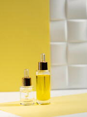 cosmetic serum and natural cosmetic oil in glass bottles on a yellow background. Skin beauty and health concept.