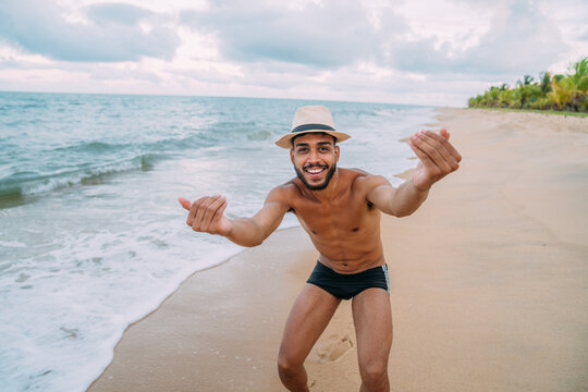 Friendly young Latin American man inviting to come to Brazil, confident and smiling making a gesture with his hand, being positive and friendly