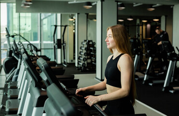 Fototapeta premium Happy athletic woman jogging on treadmills in a gym.
