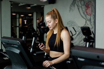 Fototapeta na wymiar Happy athletic woman jogging on treadmills in a gym.
