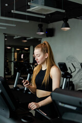 Obraz na płótnie Canvas Happy athletic woman jogging on treadmills in a gym.
