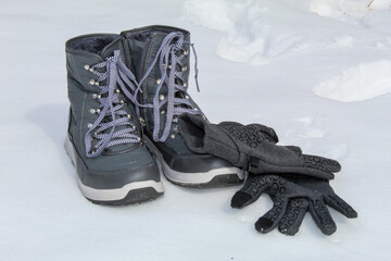 Gray winter boots, with winter gloves in snowy background