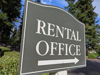 view of a sign pointing out the direction of an apartment rental office in a large community