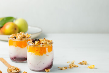 Two cups of healthy homemade yogurt with fruit and granola. Close-up, on a light background, copy of the space