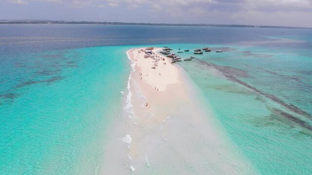 Aerial view of the paradise disappearing island of Nakupenda in Zanzibar. Sandbank in the Indian Ocean with clear turquoise water. Tourists on a white tropical sandy beach near boats in azure ocean.