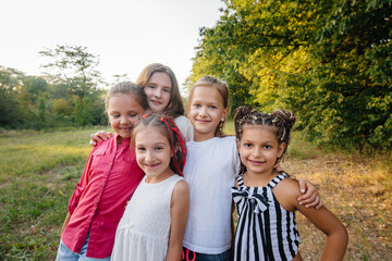 Fototapeta premium A group of cheerful girls are smiling and playing in the Park during sunset. Children's summer camp