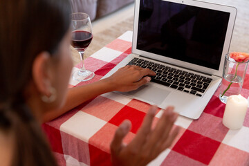 Caucasian woman sitting by desk having a video chat on laptop waving and smiling