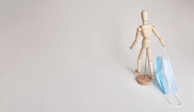 Wooden mannequin. Walking poses. An additional element is a protective mask. Light gray background