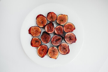 Ripe and sweet figs cut and arranged in a plate on a white background with free space. Fruits and vegetarianism