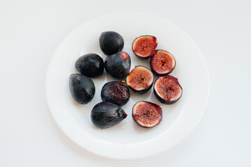 Ripe and sweet figs cut and arranged in a plate on a white background with free space. Fruits and vegetarianism