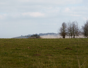 Obraz premium Challenger II main battle tank at full speed along a dusty stone track, on maneuvers in a demonstration of firepower, Salisbury Plain, Wiltshire