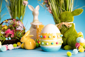 Fototapeta na wymiar Easter theme. Easter decorations. Easter eggs in basket and cabbage leaf. Bouquet of spring flowers. Blue background.
