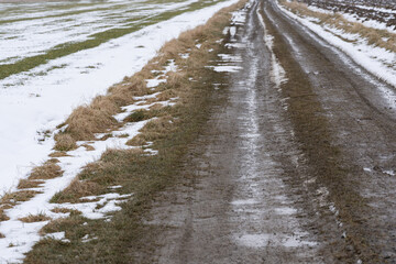 A dirt dirt road running through farmland in late winter