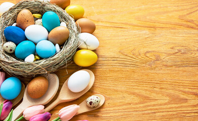 Happy Easter card. colored blue, beige, white Easter eggs in nest top view on wooden background...