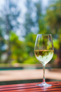 A glass of white wine on a tropical background.