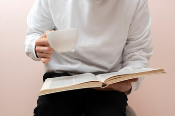 person relaxing at home, reading book and drink tea, having rest in the evening