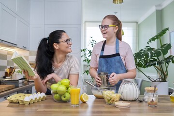Mom and teen daughter cooking apple pie together at home kitchen