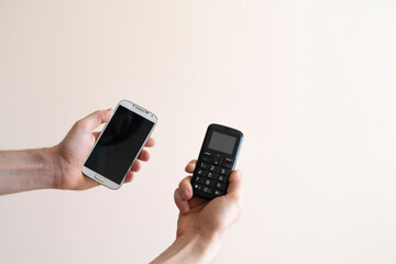 person hands holding two cell phones, vintage old and modern new, era difference