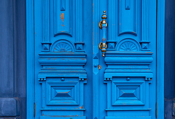 Ornate door handle with old double wood door painted in blue. Vintage wooden doorway. Classical...