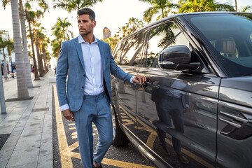 Handsome young businessman entering his car while standing outdoors on the street.