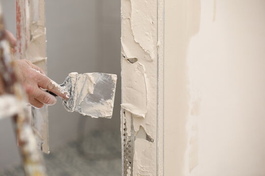 Builder using a trowel to add plaster. Plastering wall with putty-knife, close up image. Fixing wall surface and preparation for painting. construction work during quarantine