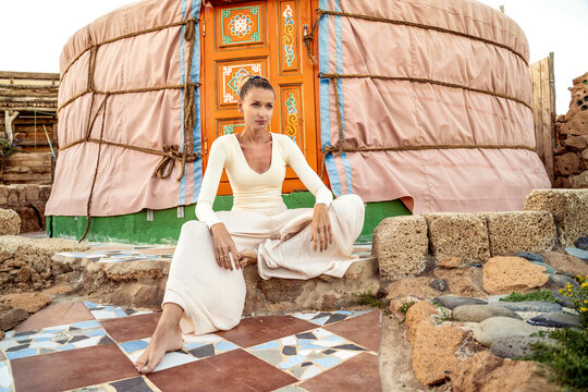 Attractive boho woman sitting and relaxing under beautiful handmade yurt.